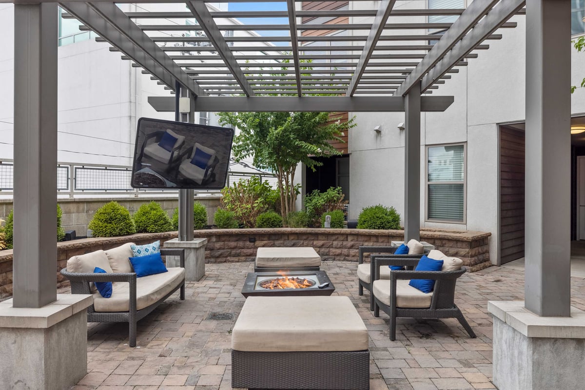 Outdoor lounge with seating, television, and grills.